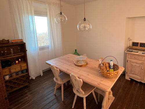 The dining room of the exclusive Guesthouse on Lake Como: four chairs around a wooden table next to a bright window.