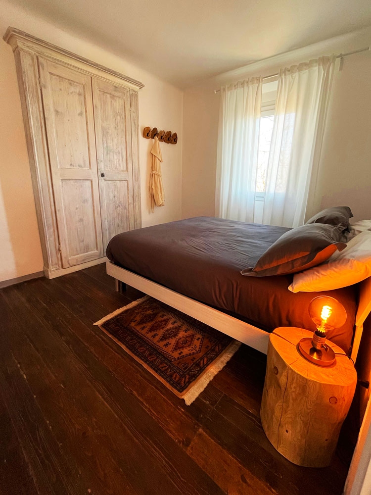 Bedroom of the exclusive Guesthouse on Lake Como: a cozy bed, a rustic bedside table and a beautiful window.