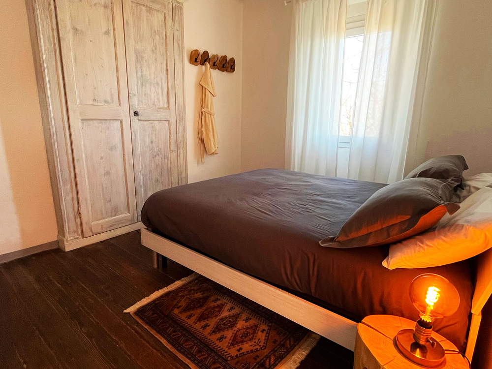 Bedroom of the exclusive Guesthouse on Lake Como: a cozy bed, a rustic bedside table and a beautiful window.